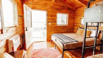A cozy cabin room with a bed, a table, and a window.