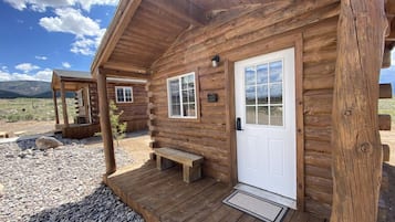 Una baita di legno con un portico, una panchina e una porta.