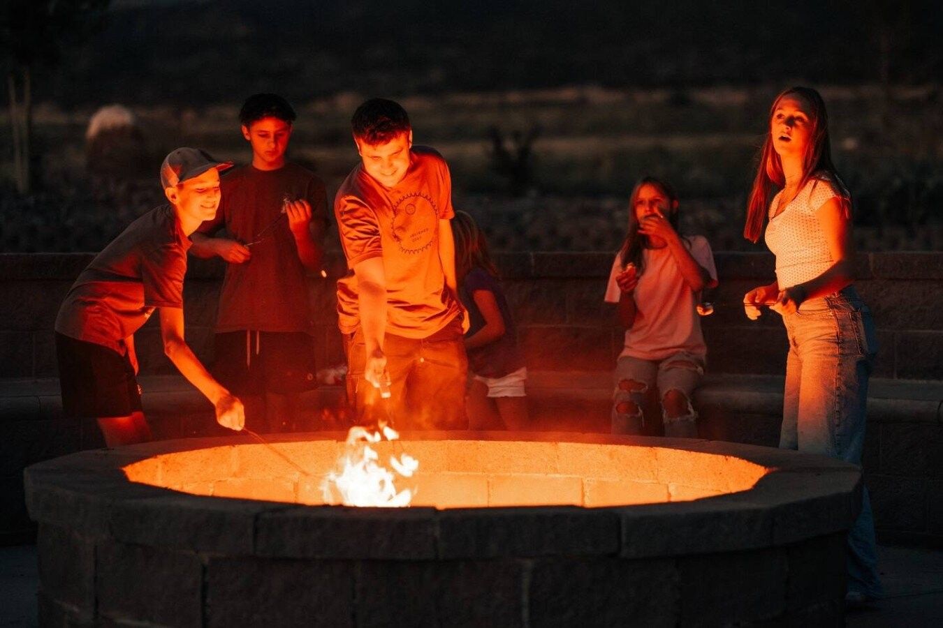 Un grupo de personas reunidas alrededor de un pozo de fuego circular al aire libre.