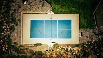 An aerial view of a rectangular swimming pool with a surrounding deck, surrounded by a landscaped garden with various plants and a pebble path.