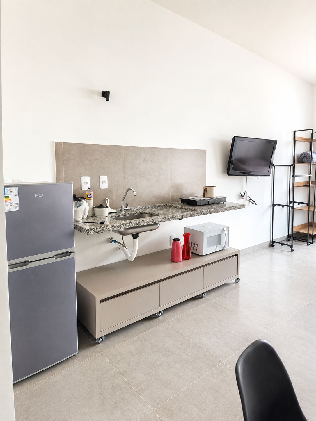 Una cucina moderna con frigorifero integrato, un piano di lavoro in granito, un lavandino e una TV a schermo piatto montata a parete.