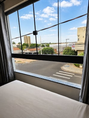 A room with a large window overlooking a street and buildings.