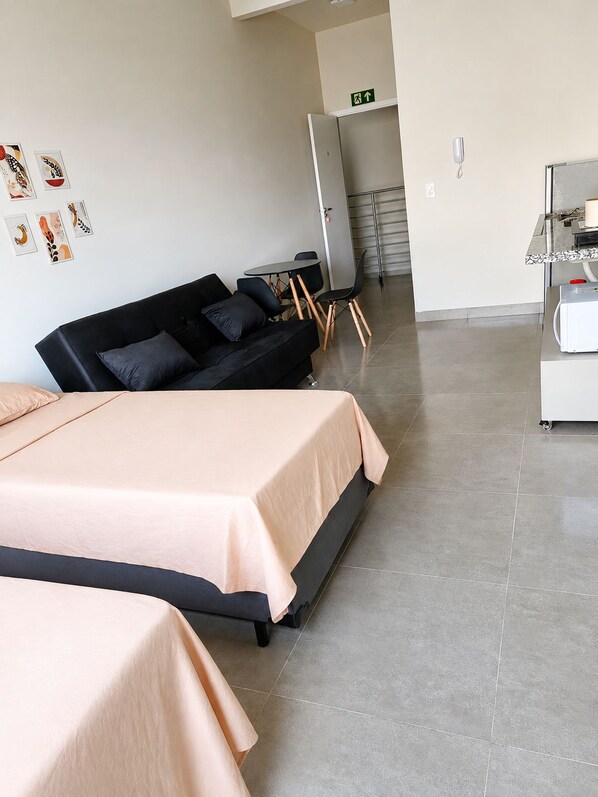 A hotel room with two beds, a black sofa, a small table, and a white cabinet. - New Listing (Iturama)