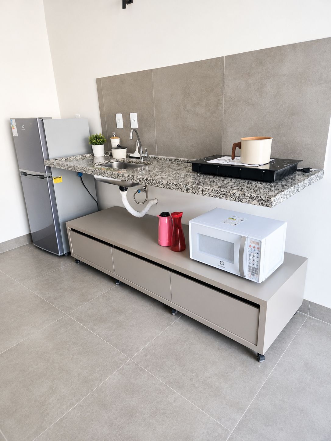 A modern kitchen with a built-in microwave, a stainless steel refrigerator, and a countertop with a sink.