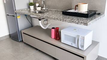 A modern kitchen with a built-in microwave, a stainless steel refrigerator, and a countertop with a sink.