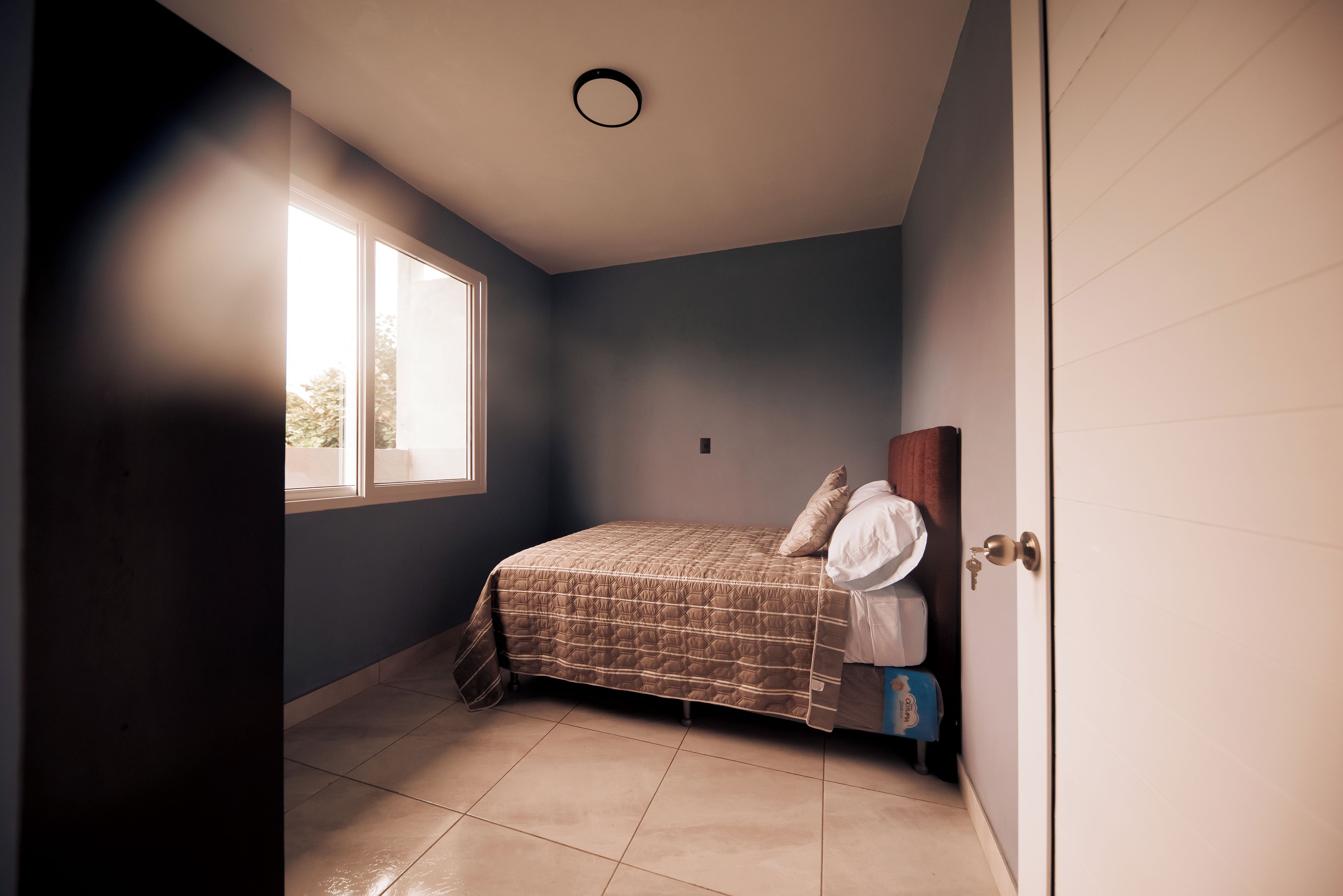 A bedroom with a bed, a window, and a door.