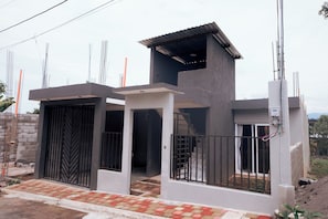 A modern two-story house with a flat roof, a gated entrance, and a visible staircase leading to the upper floor. - Family Getaway, 5 Min to IRTRA, Volcano Views + A/C (San Felipe)