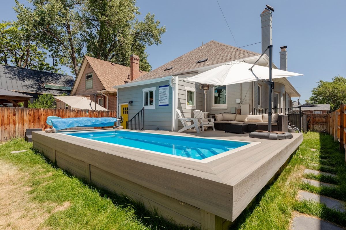 A backyard with a swimming pool, a covered patio, and a wooden deck.