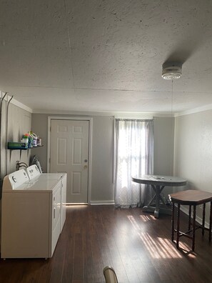 A laundry room with a washing machine, a drying rack, and a table with chairs. - Tranquil 2-bedroom cottage with AC in charming Corinth (Corinth)