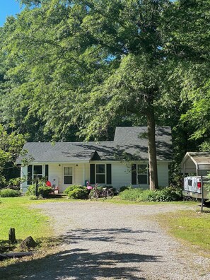 A two-story house with a gravel driveway, surrounded by trees. - Tranquil 2-bedroom cottage with AC in charming Corinth (Corinth)