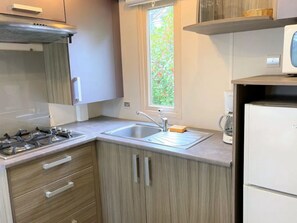 A compact kitchen with a gas stove, a sink, and a microwave. - Mobile home with AC and pets - 4 guests (Sartène)