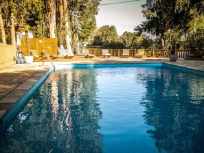 A swimming pool with lounge chairs and a wooden fence. - Cozy bungalow, pets welcome - 5 guests (Sartène)