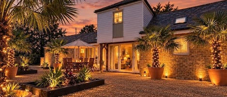 A house with a patio area, a dining set, and potted plants.
