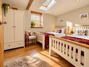 A bedroom with a skylight, a bed with a red blanket, a chair with a deer pillow, and a wardrobe. - The Granary | Luxury Countryside Retreat (Maidstone)
