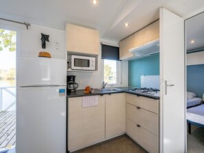 A compact kitchen with a microwave, stove, and refrigerator. - Mobile home with AC, pets welcome - 6 guests (Badefols-sur-Dordogne)
