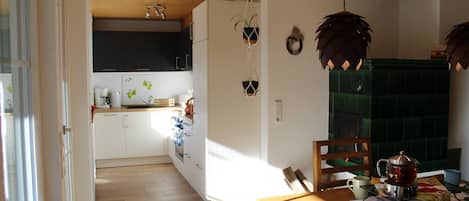 A modern kitchen with white cabinets, a wooden ceiling, and a dining area with a table set for two.