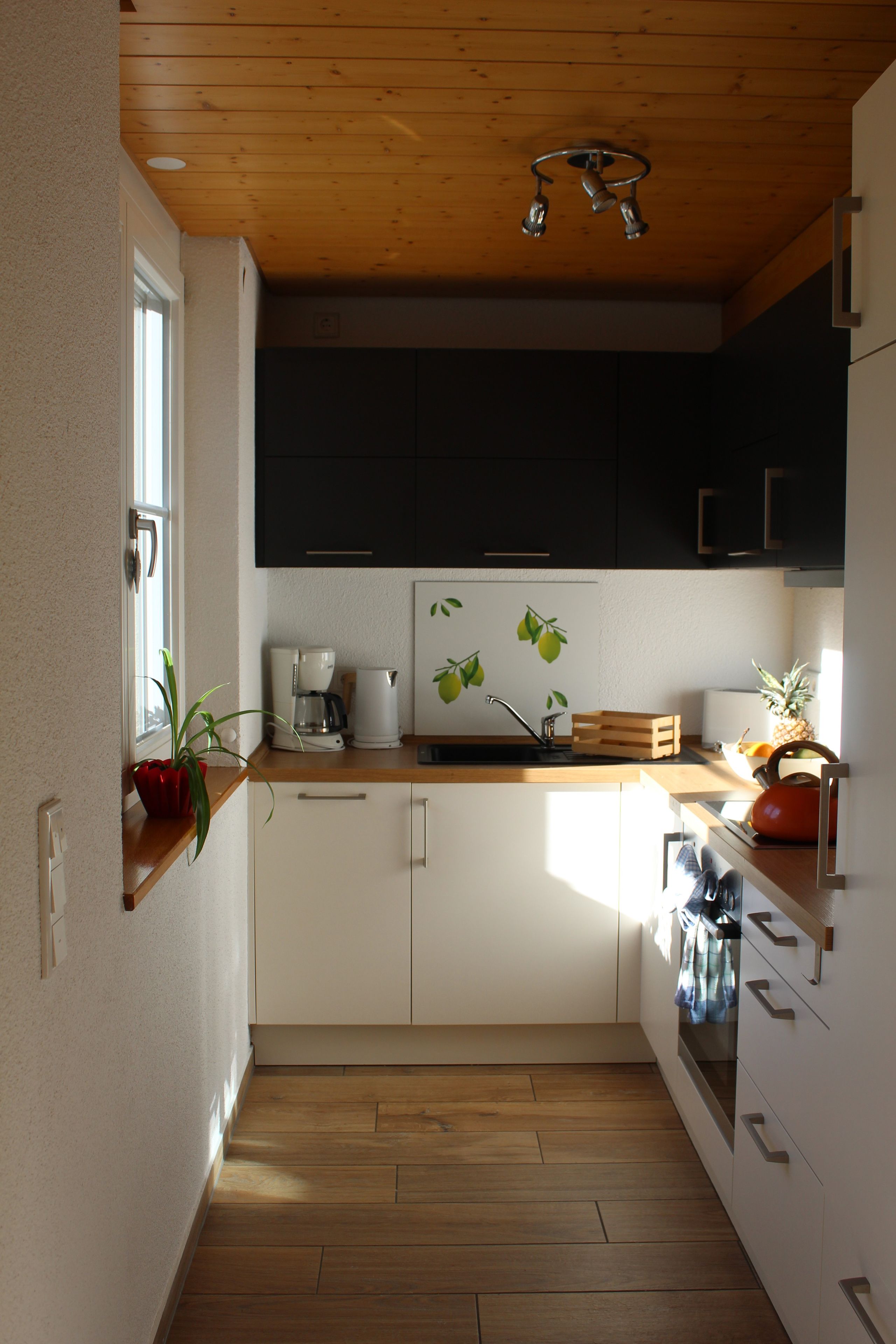 A modern kitchen with wooden cabinets, a coffee maker, and a kettle on the counter.