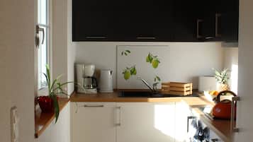 A modern kitchen with wooden cabinets, a coffee maker, and a kettle on the counter.
