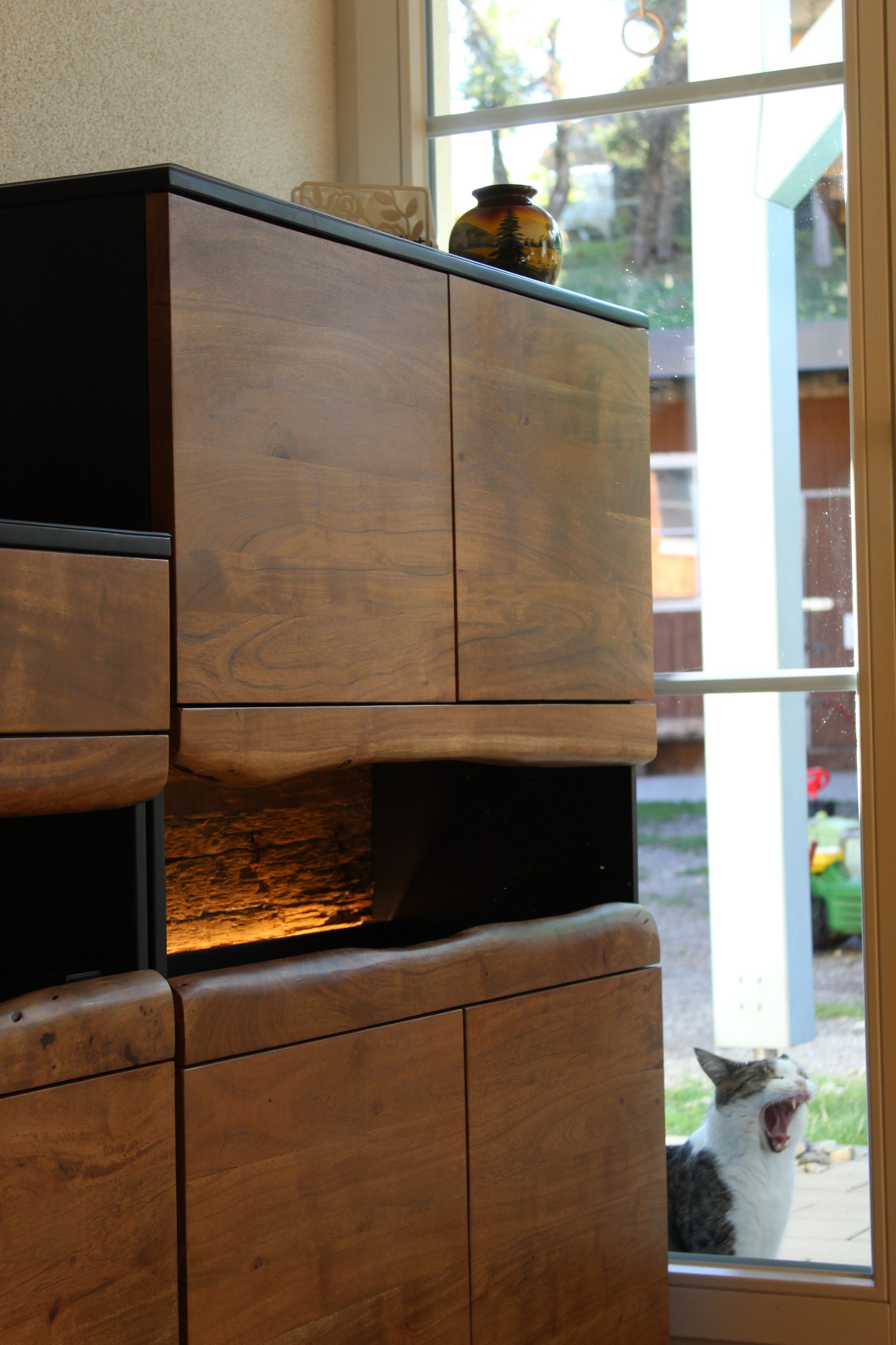 Ein Holzschrank mit einer Vase darauf.