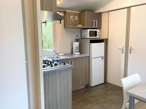 Eine kompakte Küche mit Gasherd, Mikrowelle, Kaffeemaschine und Kühlschrank.