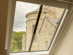 A skylight window with a view of a stone building with a rounded tower and arched windows. - Renovated apartment in town center (La Chapelle-Launay)