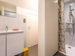 Casa de banho com chuveiro, sanita e lavatório.