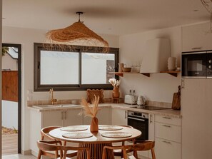 A modern kitchen with a dining table, chairs, and a hanging light fixture. - Lodge with private pool, nature - 4 guests (Salazie)