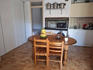 A compact kitchen with a dining area, featuring a microwave, a washing machine, and a sink. - F1 cabin with AC and parking - 5 guests (Canet-en-Roussillon)