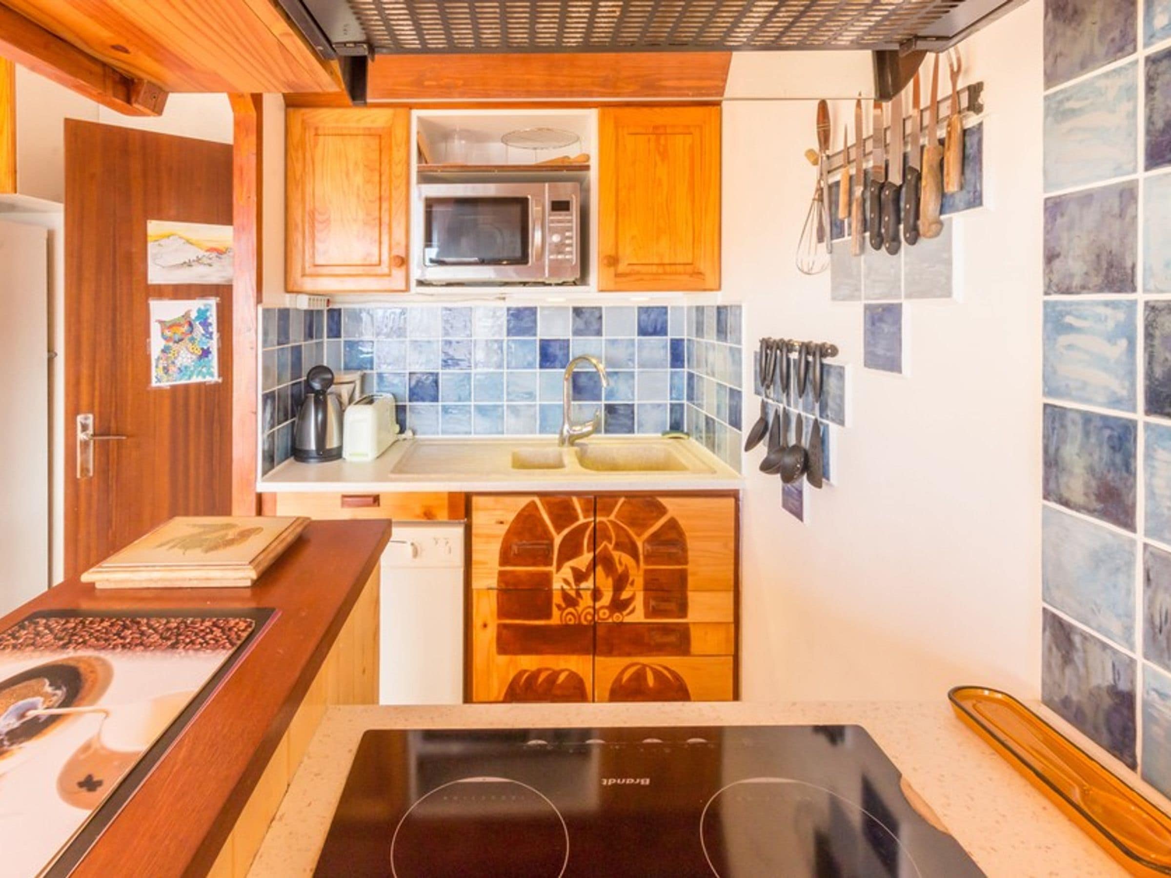 A compact kitchen with a microwave, sink, and various utensils.