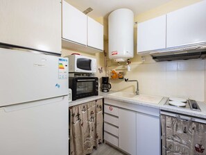 Eine kleine Küche mit Kühlschrank, Mikrowelle, Toaster und Spüle.