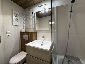 A bathroom with a toilet, a sink, a shower, and a mirror. - Luxury apartment, mountain view - 4 guests (Les Menuires)