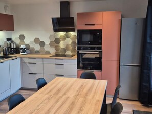 Eine moderne Küche mit einem Holztisch, schwarzen Stühlen, einem Einbauofen und einer Mikrowelle.
