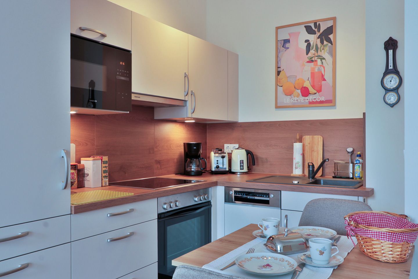 A modern kitchen with a built-in oven, a coffee maker, and a kettle on the counter.