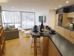 A modern kitchen with a central island, bar stools, and a dining area with a sofa and chairs. - Apartment in Tignes - 9 guests (Tignes)