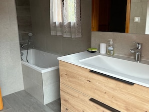 A modern bathroom with a bathtub, a vanity with a mirror, and a shower area. - Duplex, pets welcome - 8 guests (Valloire)