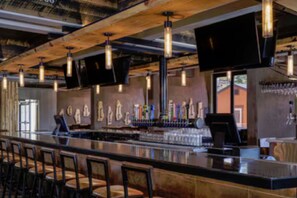 A bar area with a long counter, multiple stools, and hanging light fixtures. - 1 Unit Inside Sheraton Steamboat Resort Villas (Steamboat Springs)