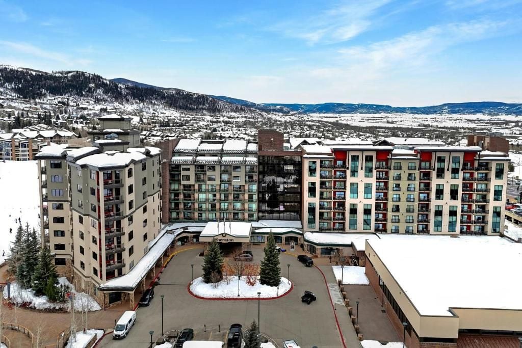 Ein Hotelkomplex mit mehreren Gebäuden, einem Parkplatz und Blick auf schneebedeckte Berge.