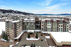 A hotel complex with multiple buildings, a parking area, and a view of snow-covered mountains. - 1 Unit Inside Sheraton Steamboat Resort Villas (Steamboat Springs)