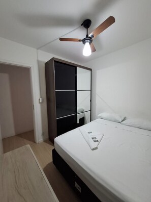 A bedroom with a bed, a wardrobe, a ceiling fan, and a light fixture. - Apartamento Vila Olímpia com 3 quartos (São Paulo)