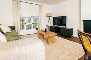 A modern living room with a large bed, a wooden coffee table, a television, and a fireplace. - Gorgeous 2BR Apartment in Central Chester (Cheshire West and Chester)