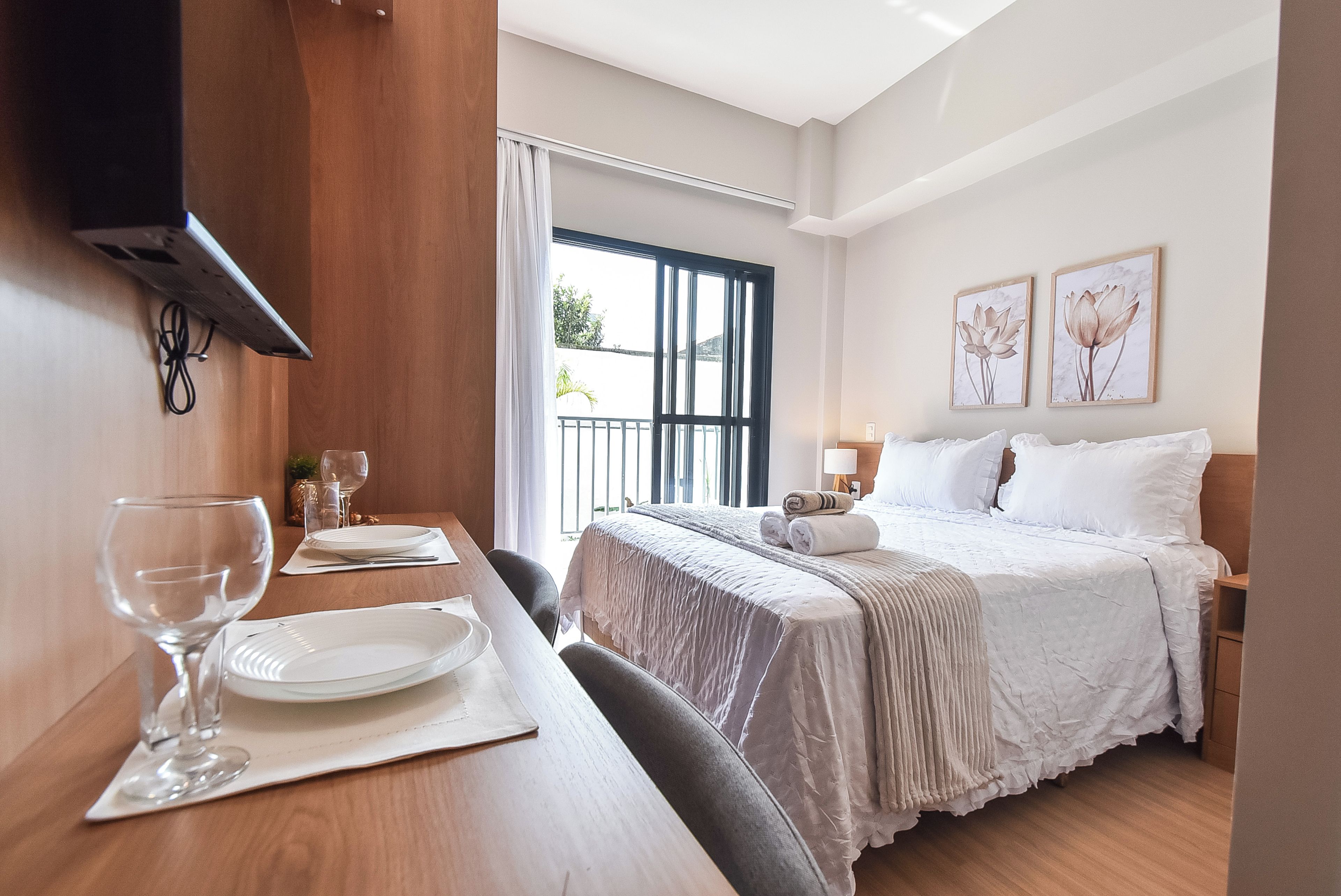A hotel room with a bed, a table with plates and glasses, and a window with curtains.