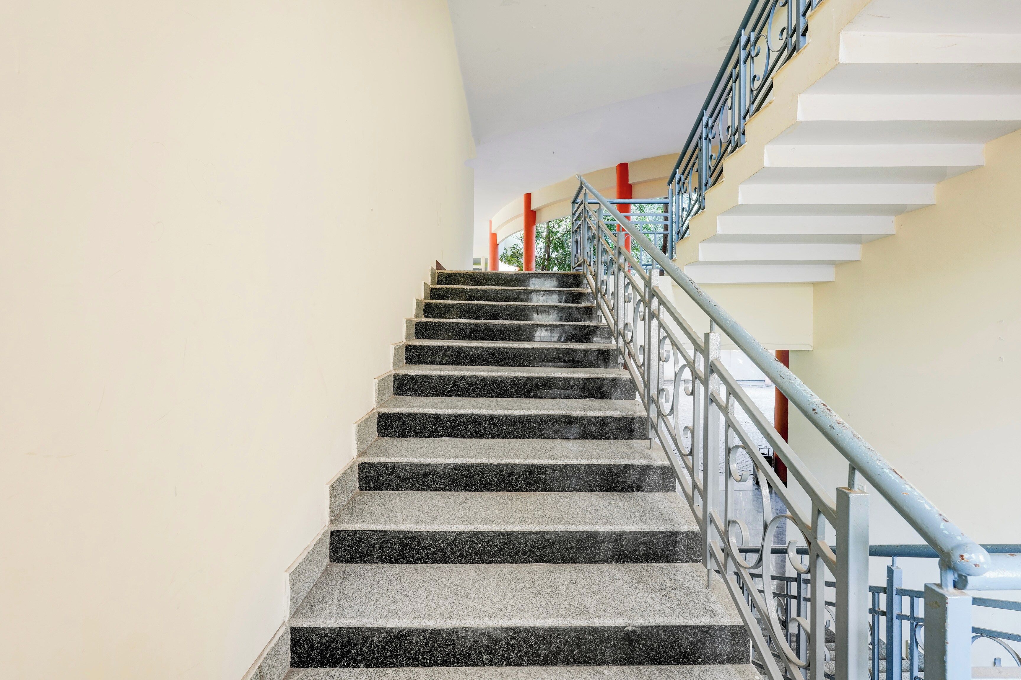 Un escalier avec des marches en granit noir et des rampes en métal, menant à l’étage supérieur.