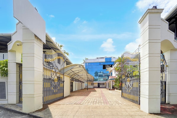 Una entrada con portón y un pasillo cubierto que conduce a un edificio con fachada de vidrio moderna.