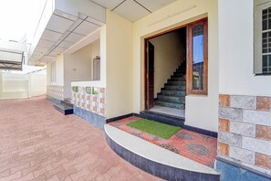 Un edificio residencial con vestíbulo empedrado, escalera y sendero pavimentado.