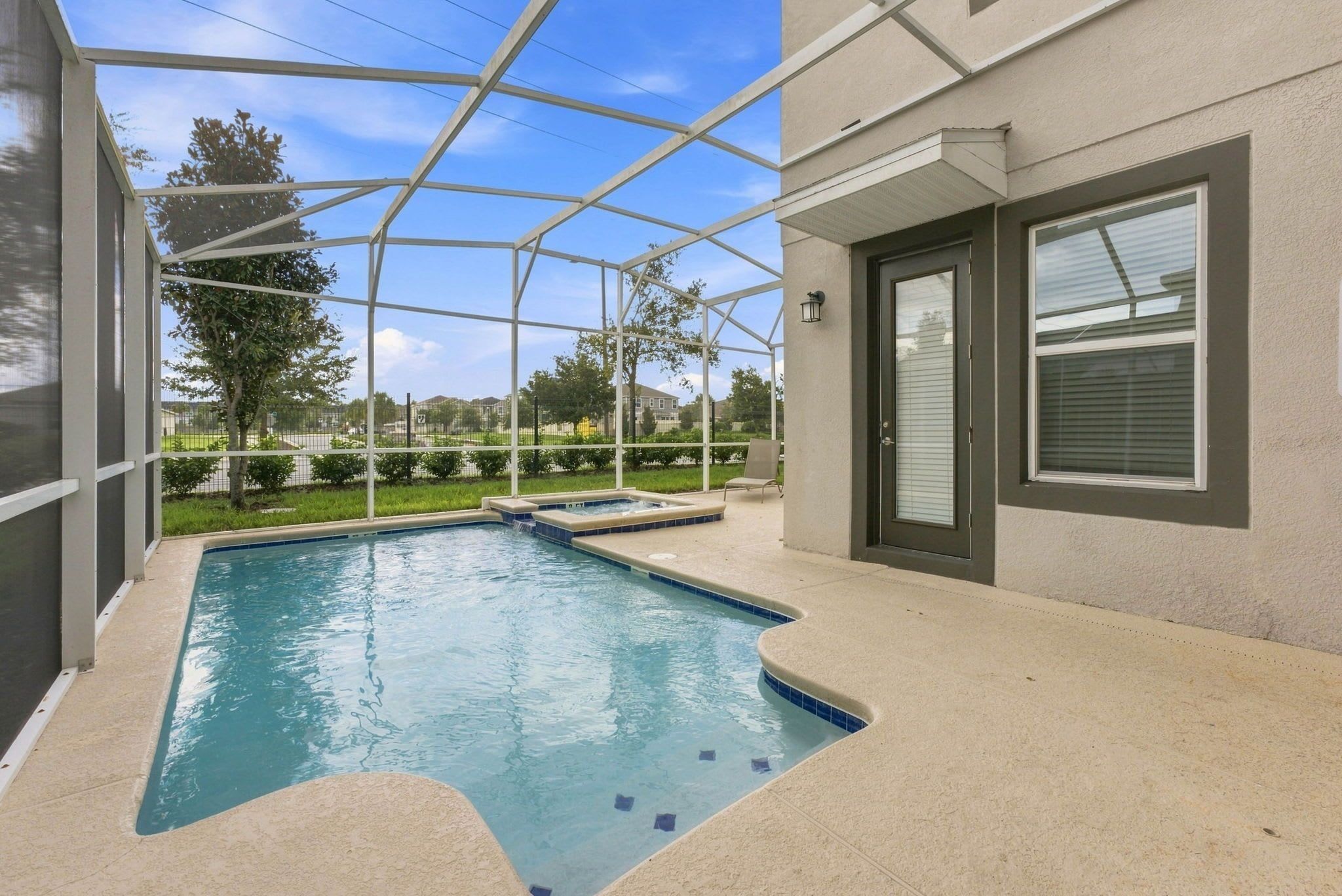 Una piscina con un jacuzzi integrado, rodeada por un área de patio techada.