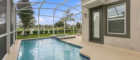 A swimming pool with a sunken hot tub, surrounded by a covered patio area.