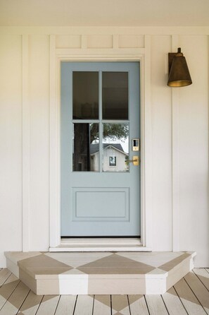 A light blue door with a glass panel, a brass doorbell, and a small mailbox on the wall. - Stardust Ranch | The Ziggy House (Fayetteville)