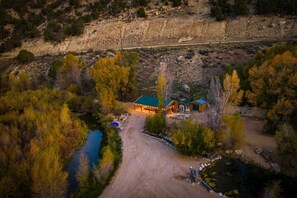 A lodge with a green roof, a dirt driveway, and a river nearby. - Stillwater Ranch - Mountain Ranch w/ River, Pond, Sauna, Stables! (Coalville)