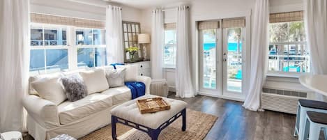 Un salon comprenant un canapé, une table basse, un ventilateur de plafond et une vue dégagée sur l’extérieur grâce à de grandes portes vitrées.