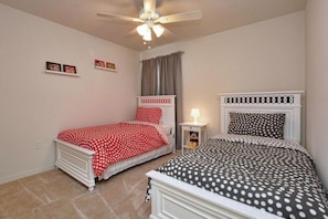 A bedroom with two beds, a ceiling fan, and a nightstand with a lamp. - Disney 4BR Home w/ Pool & Lake View (Kissimmee)